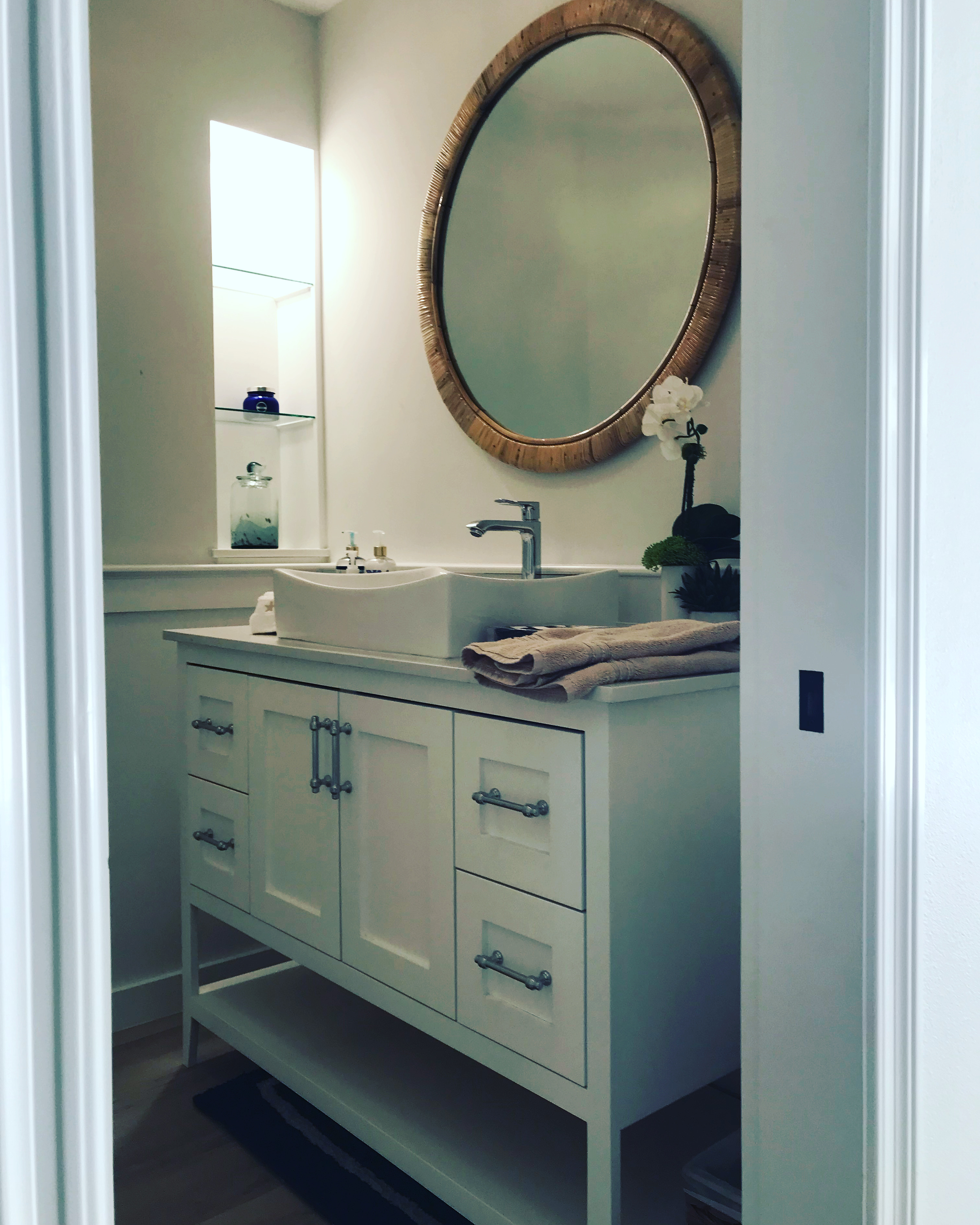 Bathroom remodel with white shaker vanity and round wood mirror