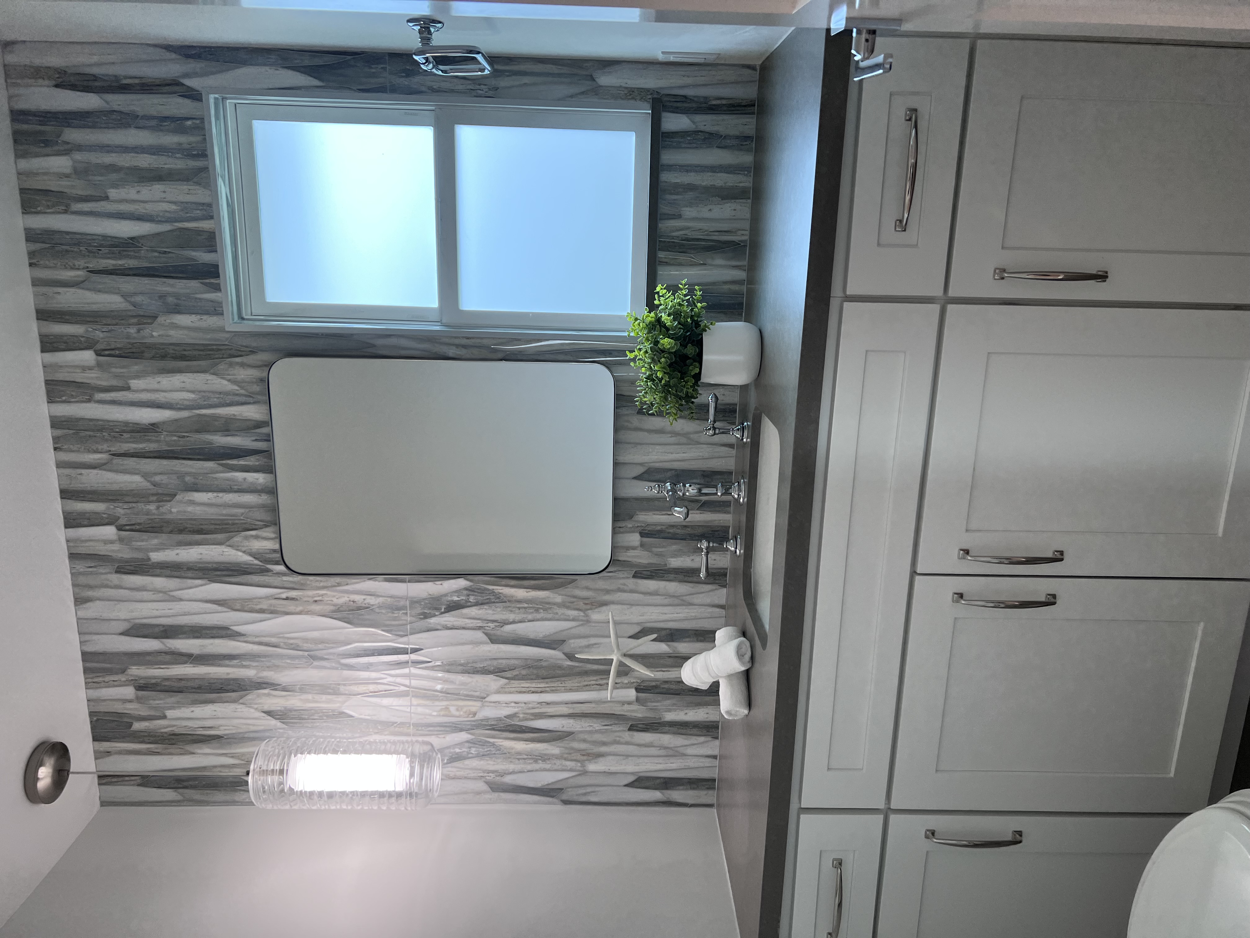 Bathroom with stone accent wall and white cabinetry