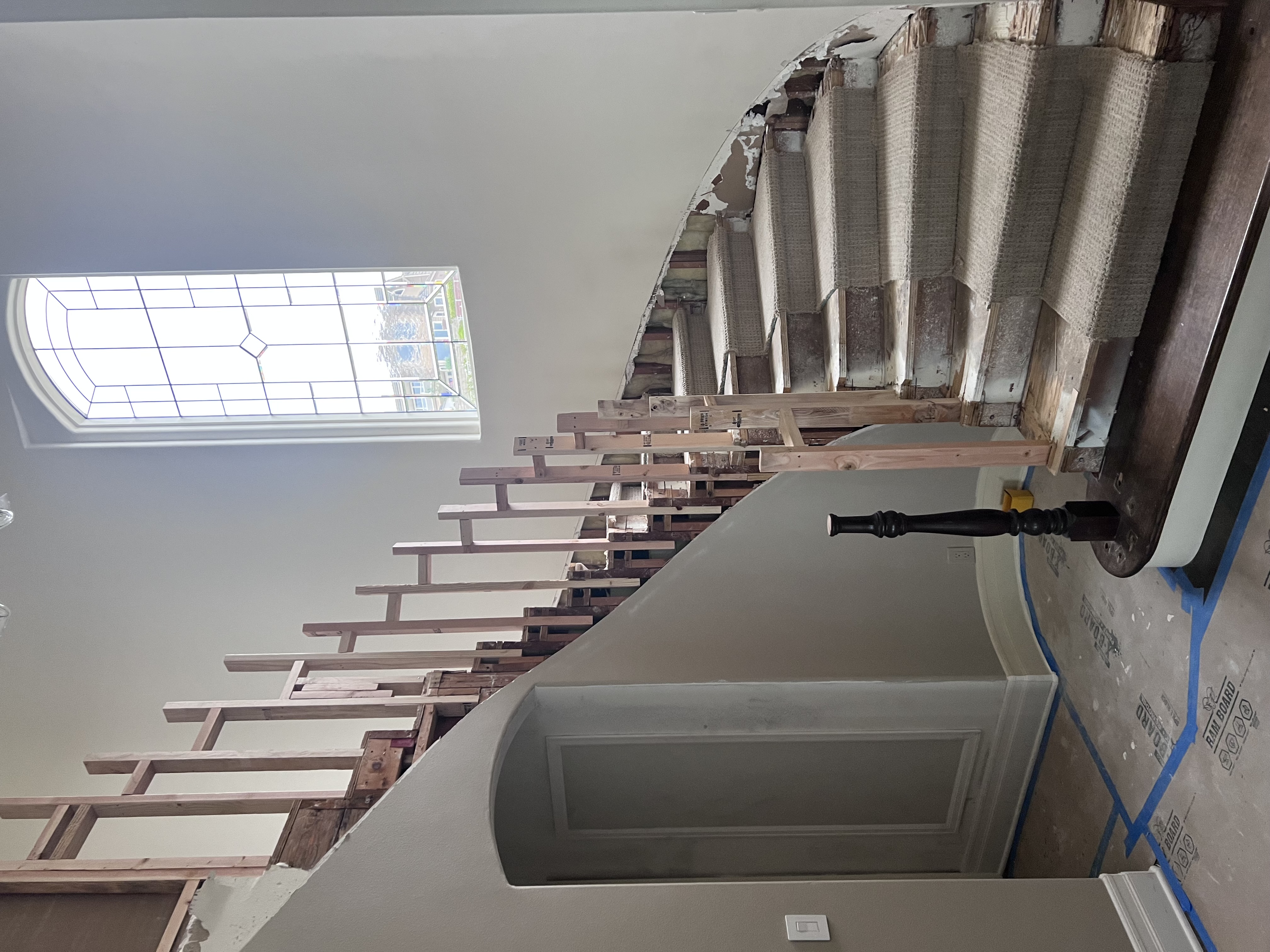 Curved staircase framing with stained glass window