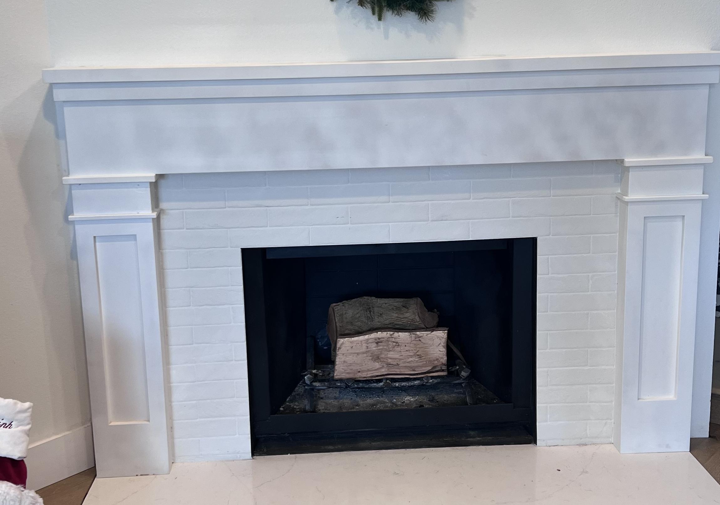 Completed white fireplace mantel with panel detail and tile surround