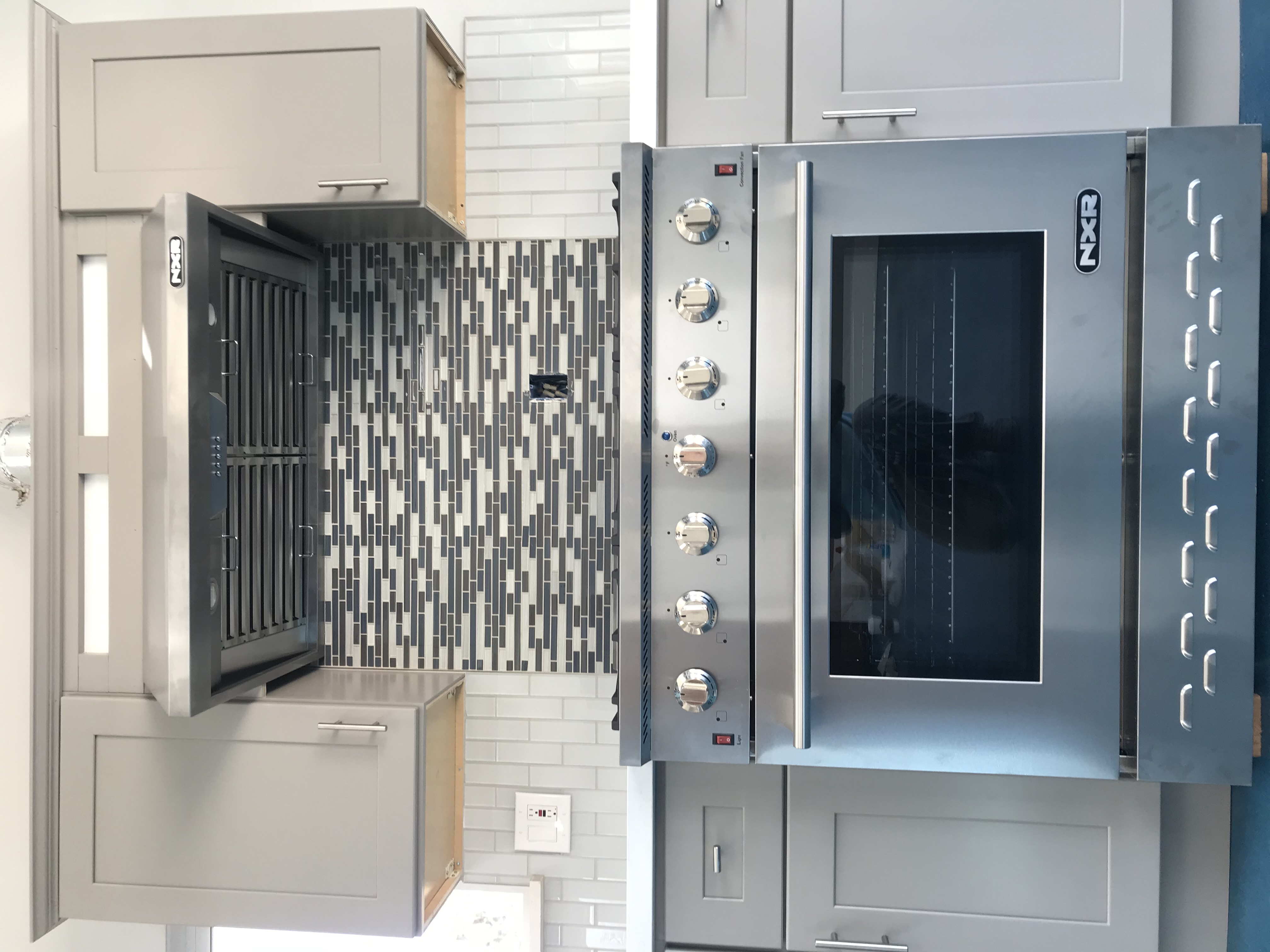 Kitchen range area with gray cabinets and mosaic tile backsplash