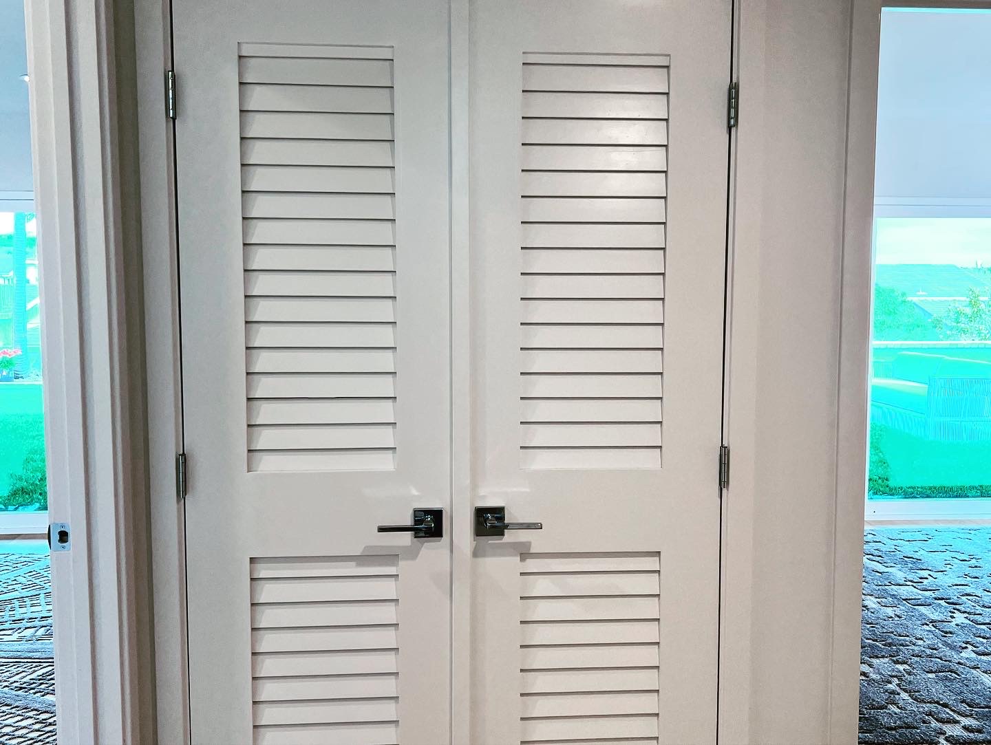 Custom white louvered double doors with chrome hardware