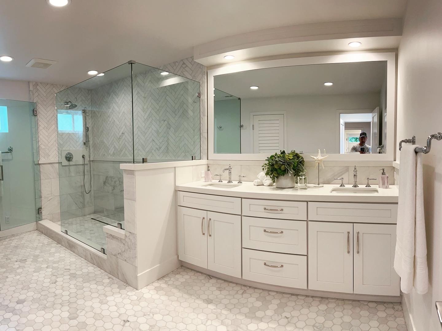 Master bathroom white vanity with arched mirror niche and glass shower